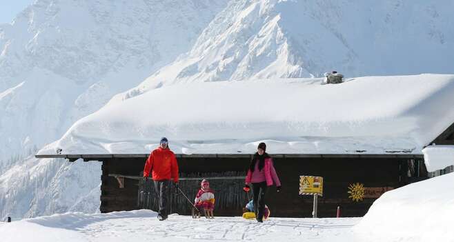 Im Winterurlaub mit den Kindern den Berg hochwandern und wieder die Piste herunterrodeln.